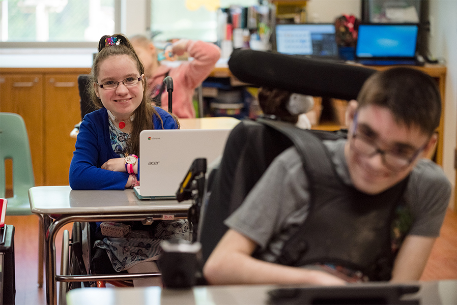 A female and male student, both in wheelchairs, in a classroom setting