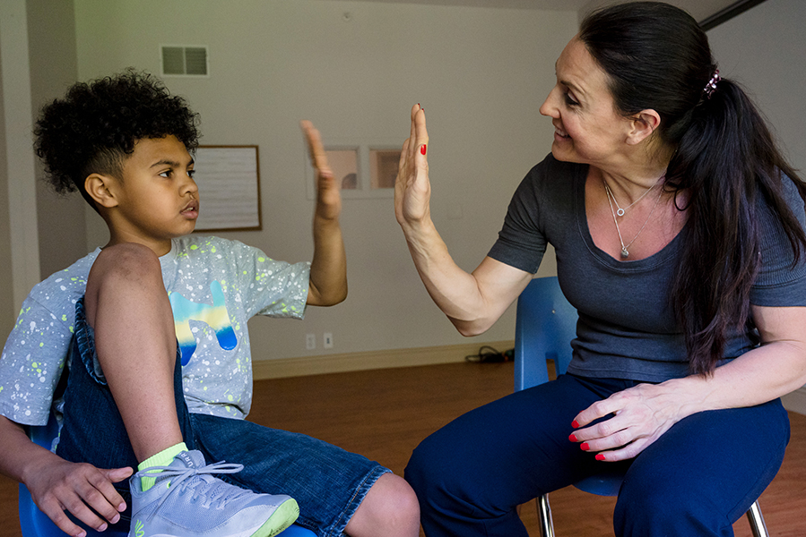 A young male student and a teacher giving each other a high five. 