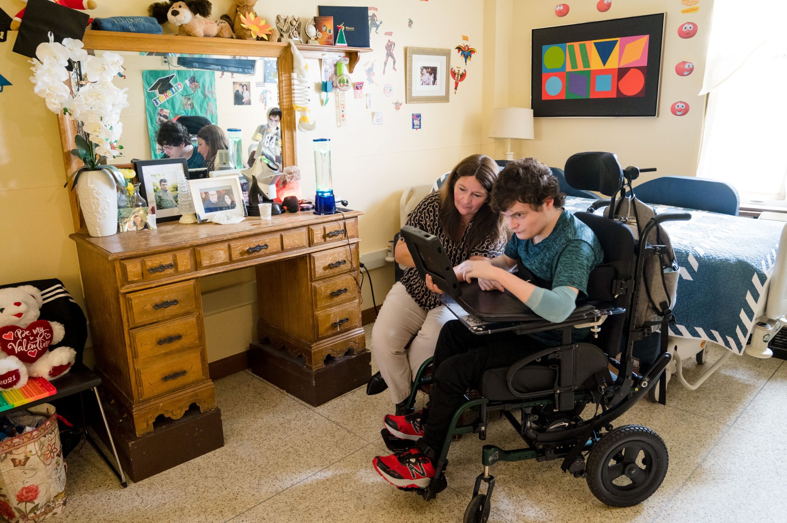 A McGuire Memorial team member and a resident in a wheelchair are working on a computer together. 