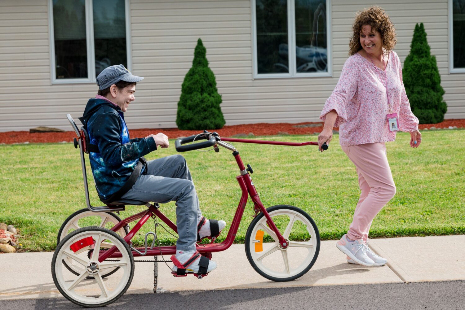 A McGuire Memorial program instructor helping a LEAP participant ride a bike outside.