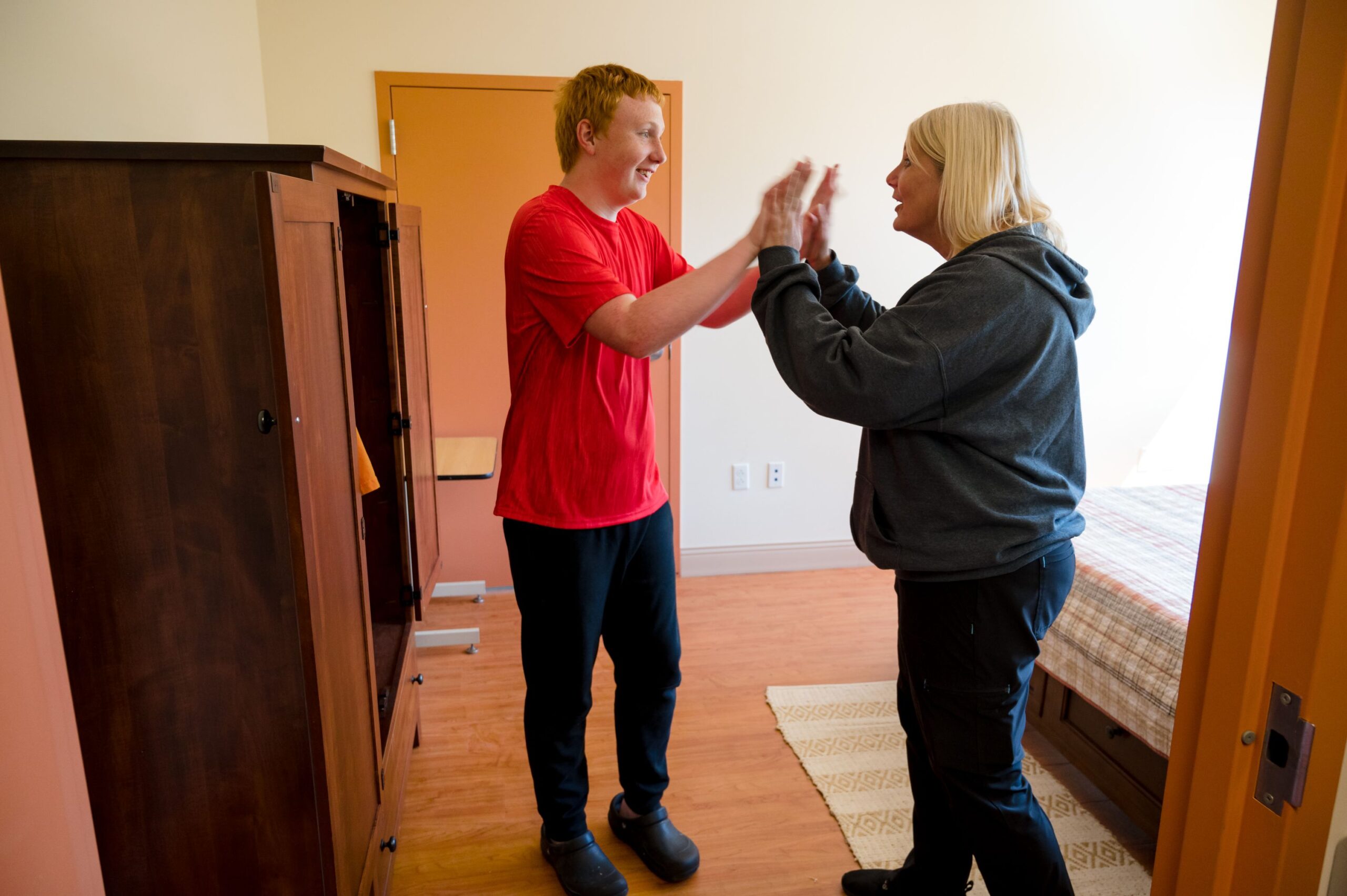 A young male McGuire Memorial resident and a McGuire Memorial team member giving each other high-fives