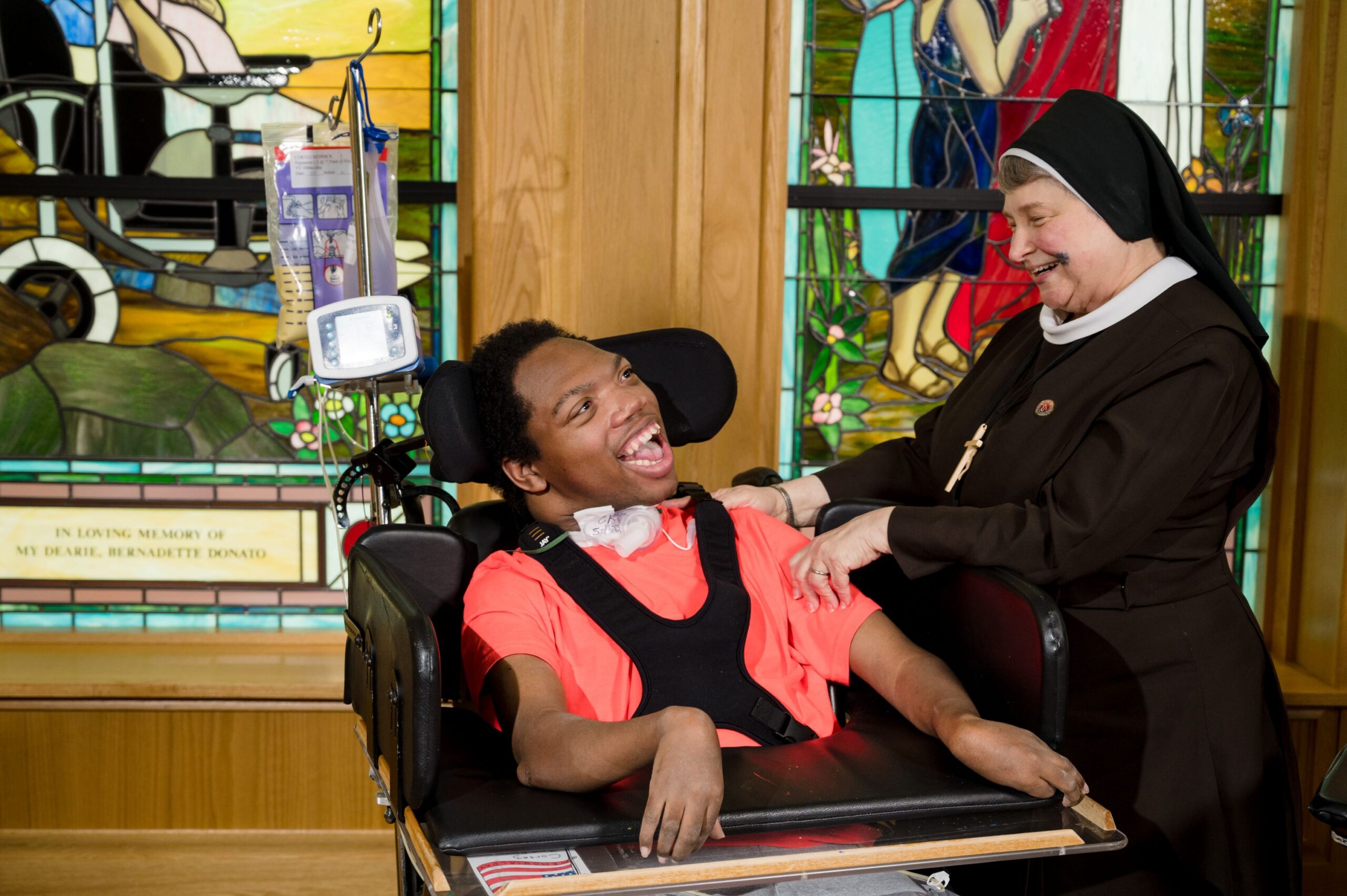 A young man in a wheelchair with a nun inside the McGuire Memorial chapel