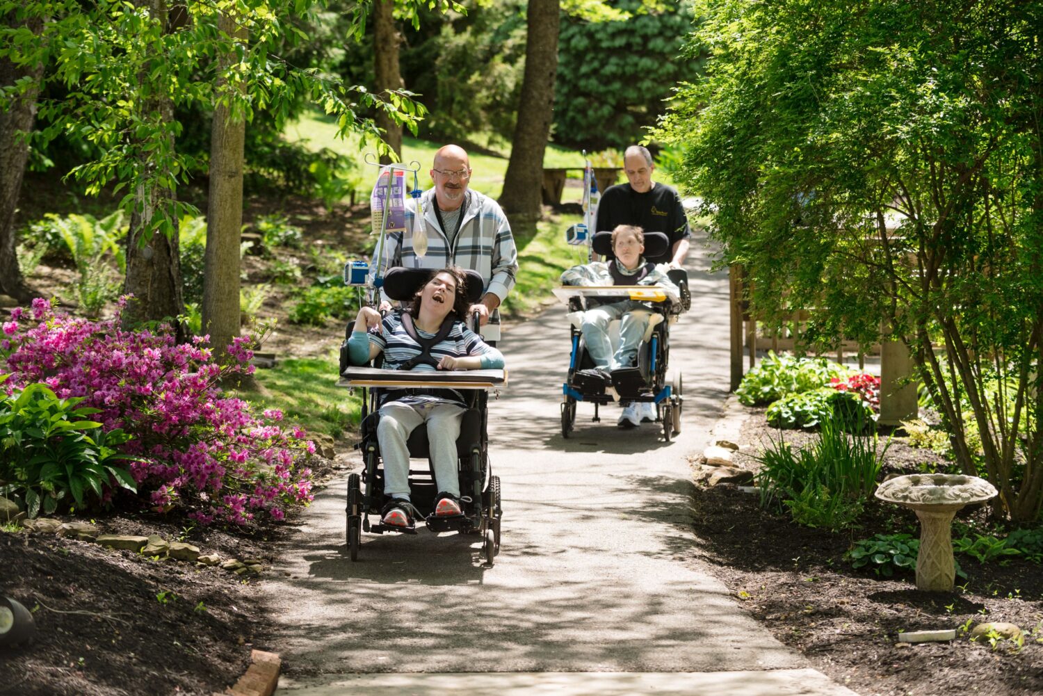 Two McGuire Memorial team members are pushing two residents in wheelchairs down the St. Francis Nature Trail. 