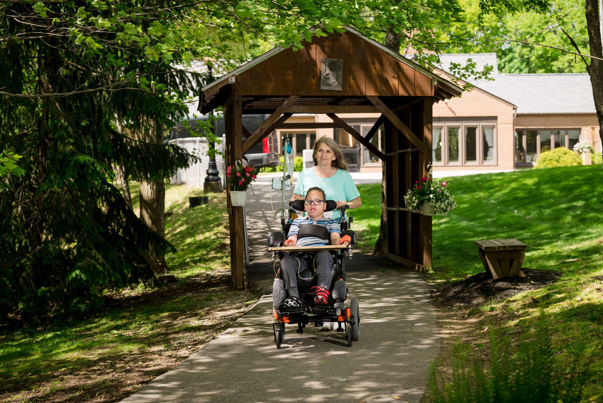 A McGuire Memorial team member pushing a boy in a wheelchair on the St. Francis nature trail